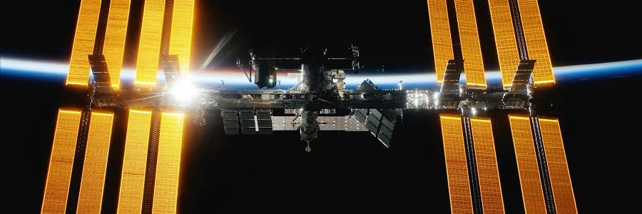 International Space Station illuminated by sunlight above Earth's horizon in space.